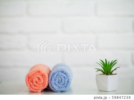 Fluffy bath towels on light wooden table with decor and white background 59847239