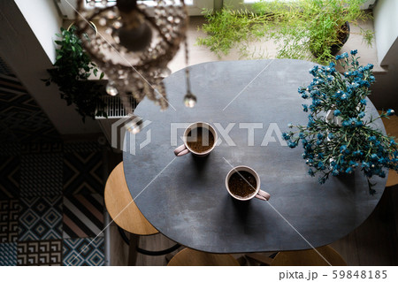 Two ceramic white cups of coffee standing on a wooden oval table Two ceramic white cups of coffee standing on a wooden oval table 59848185