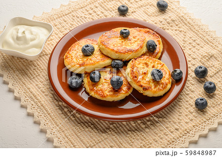 Homemade cheesecakes on a plate with berries and syrup close-up. Healthy food Homemade cheesecakes on a plate with berries and syrup close-up. Healthy food 59848987