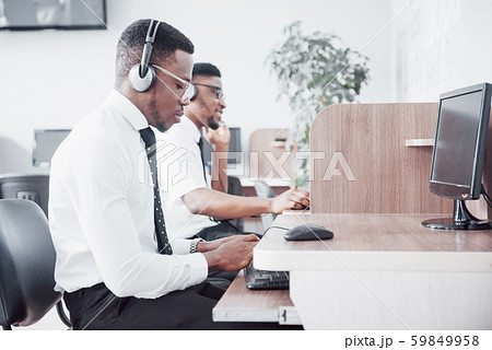 African american customer support operator with hands-free headset working in the office African american customer support operator with hands-free headset working in the office 59849958
