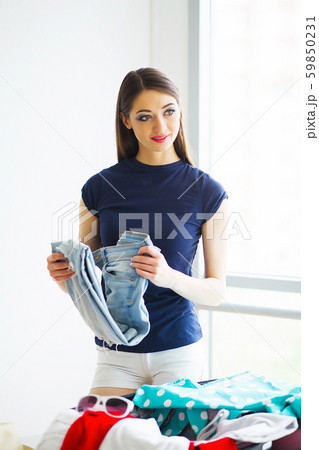 Beautiful woman is packing clothing in suitcase at home Beautiful woman is packing clothing in suitcase at home 59850231