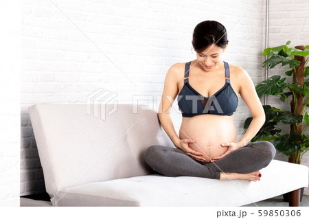 Cheerful Asian pregnant woman in sportswear touching baby inside stomach 59850306