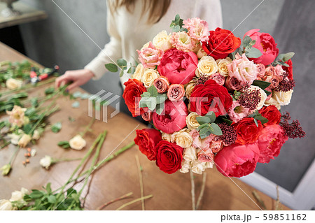 European floral shop concept. Florist woman creates red beautiful bouquet of mixed flowers. Handsome European floral shop concept. Florist woman creates red beautiful bouquet of mixed flowers. Handsome 59851162