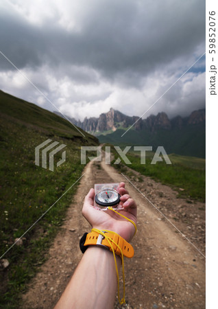 Close-up wide angle male hand with a yellow watch bracelet holds a magnetic navigation compass 59852076