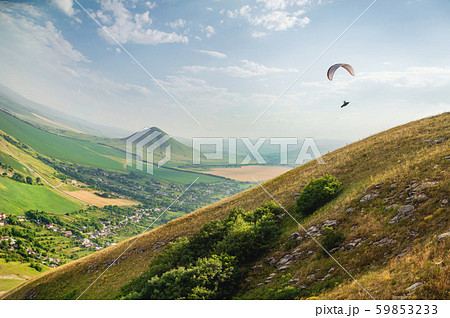 A paraglider flies in the sky in a cocoon suit on a paraglider over the Caucasian countryside with 59853233