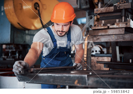 Portrait of a young worker in a hard hat at a large waste recycling factory. The engineer monitors 59853842