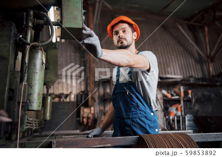 Portrait of a young worker in a hard hat at a large waste recycling factory. The engineer monitors Portrait of a young worker in a hard hat at a large waste recycling factory. The engineer monitors 59853892