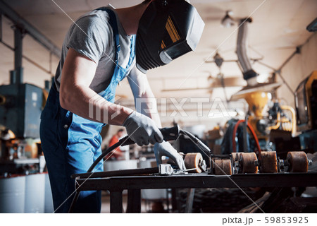 Portrait of a young worker at a large metalworking plant. The welder engineer works in a protective Portrait of a young worker at a large metalworking plant. The welder engineer works in a protective 59853925