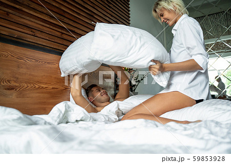 Happy woman is holding pillows in hands in bedroom Happy woman is holding pillows in hands in bedroom 59853928