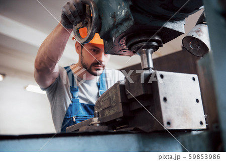Portrait of a young worker in a hard hat at a large waste recycling factory. The engineer monitors Portrait of a young worker in a hard hat at a large waste recycling factory. The engineer monitors 59853986