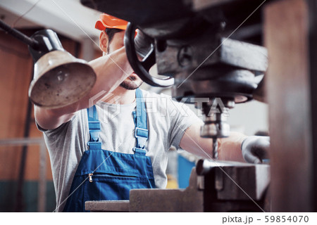 Portrait of a young worker in a hard hat at a large waste recycling factory. The engineer monitors Portrait of a young worker in a hard hat at a large waste recycling factory. The engineer monitors 59854070