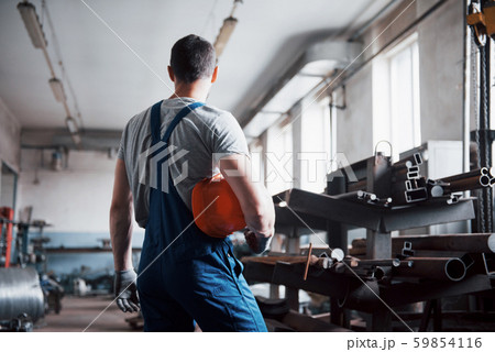 Portrait of a young worker in a hard hat at a large waste recycling factory. The engineer monitors Portrait of a young worker in a hard hat at a large waste recycling factory. The engineer monitors 59854116