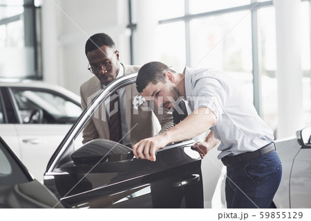 An African man who buys a new car checks a car talking to a professional vendor. 59855129