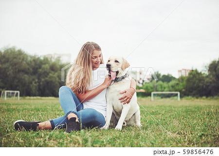 Attractive young woman with labrador outdoors. Woman on a green grass with dog labrador retriever 59856476