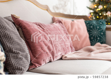 Closeup of pilows laying on sofa with decorated christmas tree on background. Selective focus 59857238