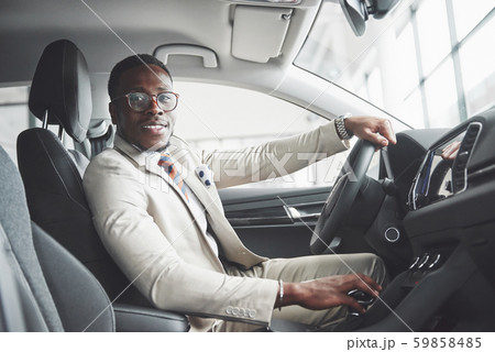 Stylish black businessman sitting behind the wheel of new luxury car. Rich african american man Stylish black businessman sitting behind the wheel of new luxury car. Rich african american man 59858485