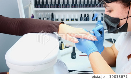 Manicurist makes gel polish on the nails of a clint, close-up Manicurist makes gel polish on the nails of a clint, close-up 59858671
