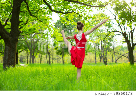 Young sports girl in a red dress practices yoga in 59860178