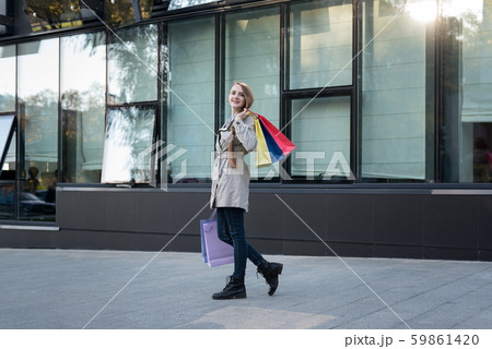 Happy young woman with colorful bags near mall. 59861420