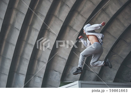 A young man is jumping. Parkour in urban space, sporting activity. 59861663