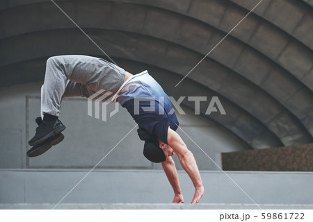 The man outdoors practices parkour, extreme acrobatics. 59861722