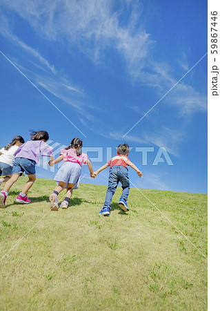 公園の丘を登る子供たちの後ろ姿の写真素材