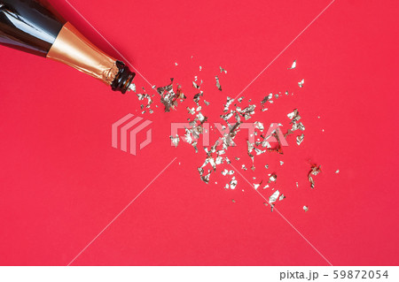 Bottle of sparkling wine and gold glitter on red background, top view. Bottle of sparkling wine and gold glitter on red background, top view. 59872054