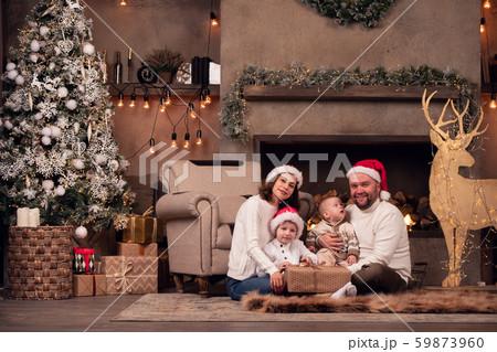 Photo of parents in Santa's cap with two sons sitting on floor by fireplace next to deer with Photo of parents in Santa's cap with two sons sitting on floor by fireplace next to deer with 59873960