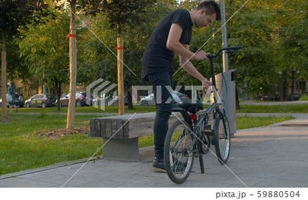 Man prepares folding bike for ride Man prepares folding bike for ride 59880504