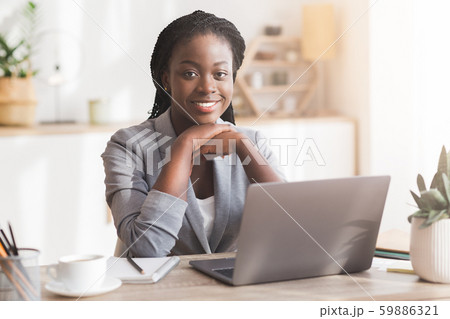 Young African Businesswoman Smiling Sitting At Workplace In Modern Office Young African Businesswoman Smiling Sitting At Workplace In Modern Office 59886321