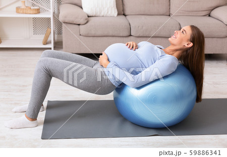 Pregnant girl working out with fitness ball at home Pregnant girl working out with fitness ball at home 59886341
