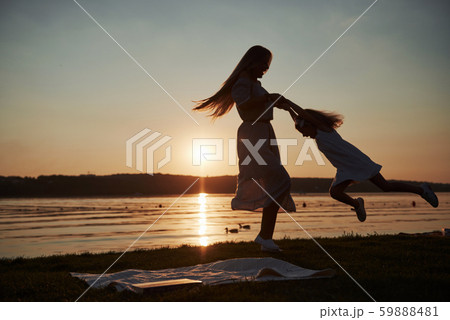 Mom plays with her baby on holidays near the ocean, silhouettes at sunset 59888481