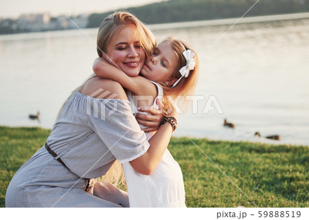 Happy young mother with a playful daughter in a park near the water 59888519