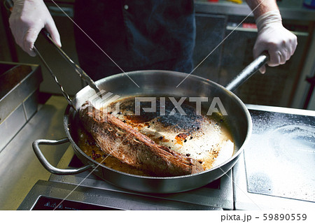 The chef works in the kitchen of the restaurant. Fresh meat roasted in a large frying pan The chef works in the kitchen of the restaurant. Fresh meat roasted in a large frying pan 59890559