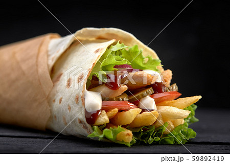 Tasty doner kebabs with fresh salad trimmings and shaved roasted meat served in tortilla wraps on 59892419