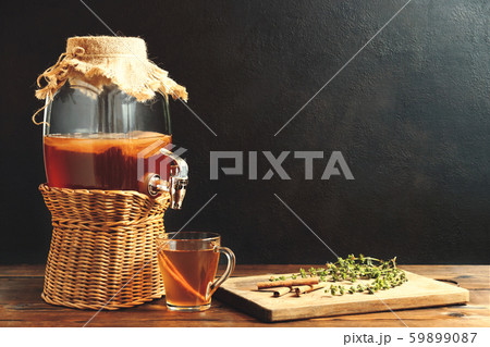 Fresh homemade Kombucha fermented tea drink in jar with faucet and in cup on dark background 59899087