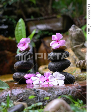 Stack of zen stones with flowers next to a garden Stack of zen stones with flowers next to a garden 59900743