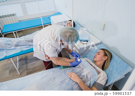 Professional nurse making an injection to a woman lying on operating table at the hospital preparing Professional nurse making an injection to a woman lying on operating table at the hospital preparing 59901537