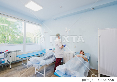 Nurse connecting an intravenous drip in hospital room. 59901556