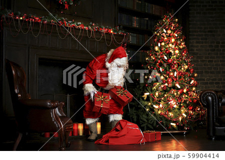 Christmas night, Santa Claus puts gifts under the tree Christmas night, Santa Claus puts gifts under the tree 59904414