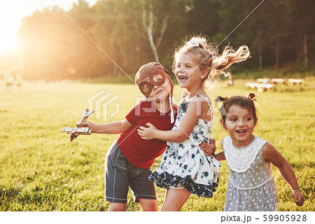 Brother and two sisters are playing together. Three children playing with a wooden airplane outdoor 59905928