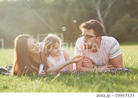 Mother and father spend time together happily. Little daughter plays with her parents outdoors Mother and father spend time together happily. Little daughter plays with her parents outdoors 59907335