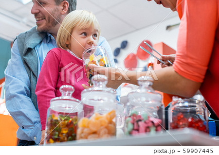 Saleslady for sweet things handing some candy to a kid Saleslady for sweet things handing some candy to a kid 59907445