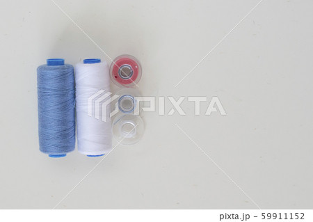 Colored bobbins and spools of thread for machine sewing on a light background close-up Colored bobbins and spools of thread for machine sewing on a light background close-up 59911152