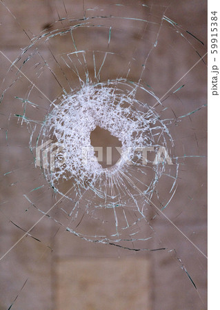Hole in broken glass on a dark beige background. Hole in broken glass on a dark beige background. 59915384