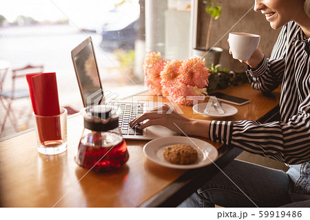 Cheerful woman working remotely from the cafe 59919486