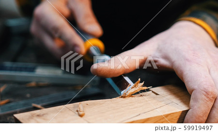 Carpentry - a woodworker cutting out the recess on the wooden block with a chisel Carpentry - a woodworker cutting out the recess on the wooden block with a chisel 59919497