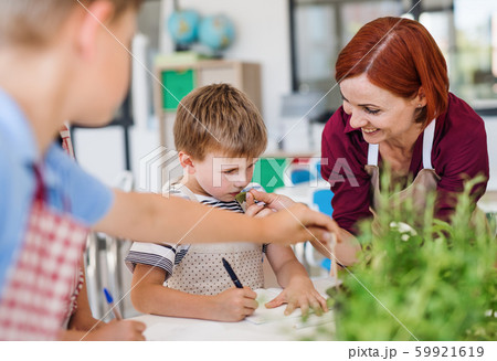 Group of small school kids with teacher in class, learning about plants. 59921619