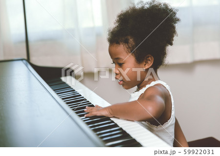 little child girl touching looking at the piano interested impression with music instrument. 59922031