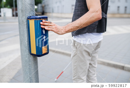 Midsection of blind man with white cane at pedestrain crossing in city. Midsection of blind man with white cane at pedestrain crossing in city. 59922817